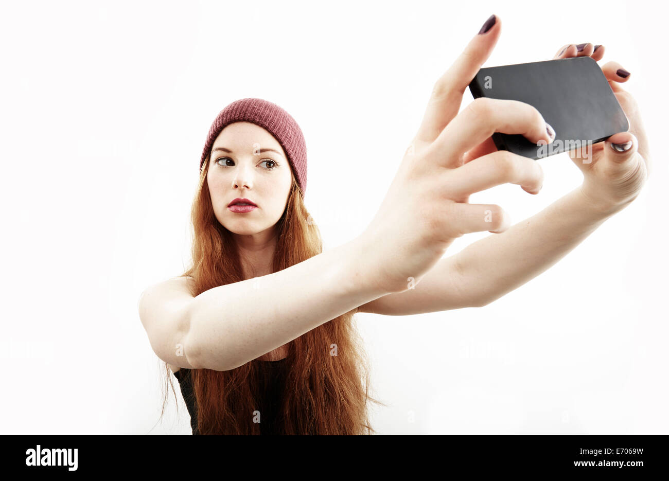 Studio portrait of young woman making sur smartphone selfies Banque D'Images