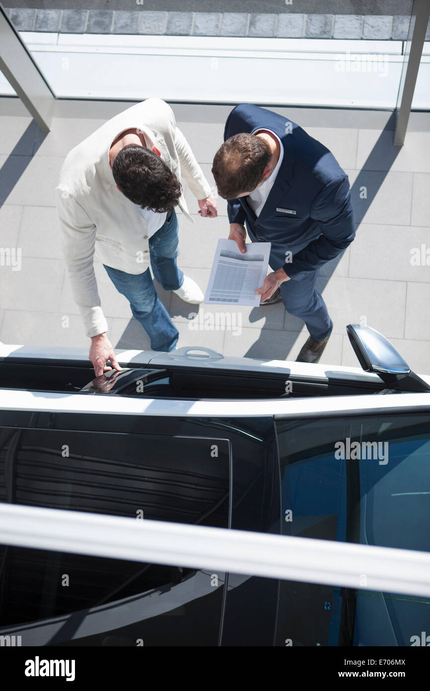 Vue de dessus de vendeur et le client à la recherche de nouvelles voiture dans l'agence de voiture Banque D'Images
