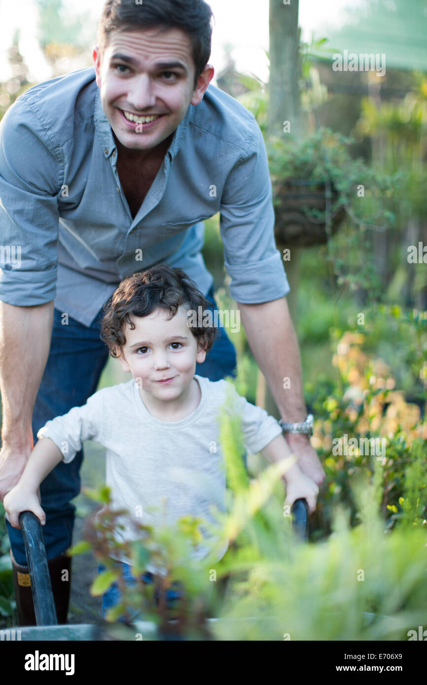 Portrait of mid adult man et fils pushing wheelbarrow in allotment Banque D'Images