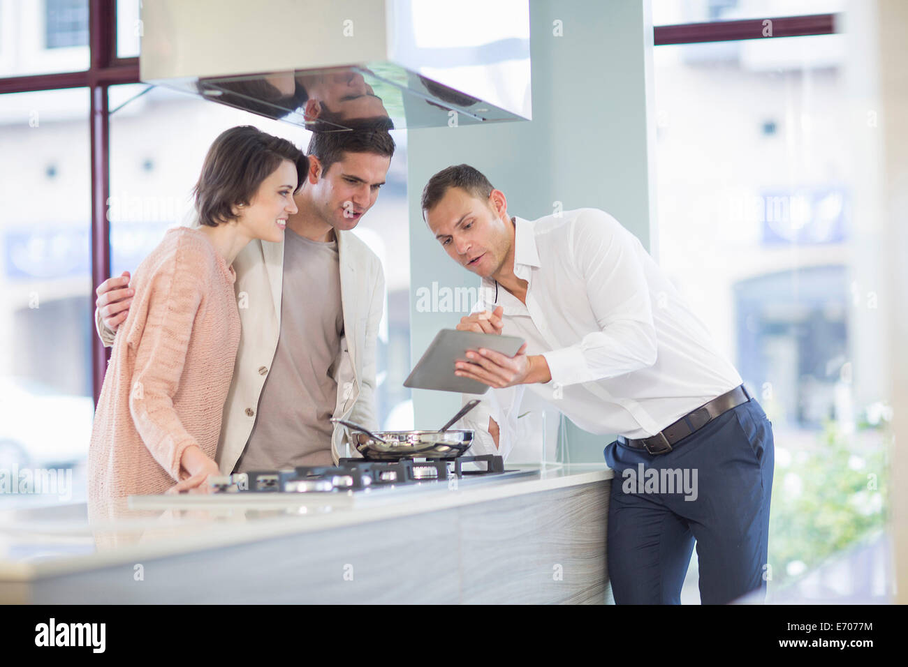 Couple et vendeur looking at digital tablet in kitchen showroom Banque D'Images