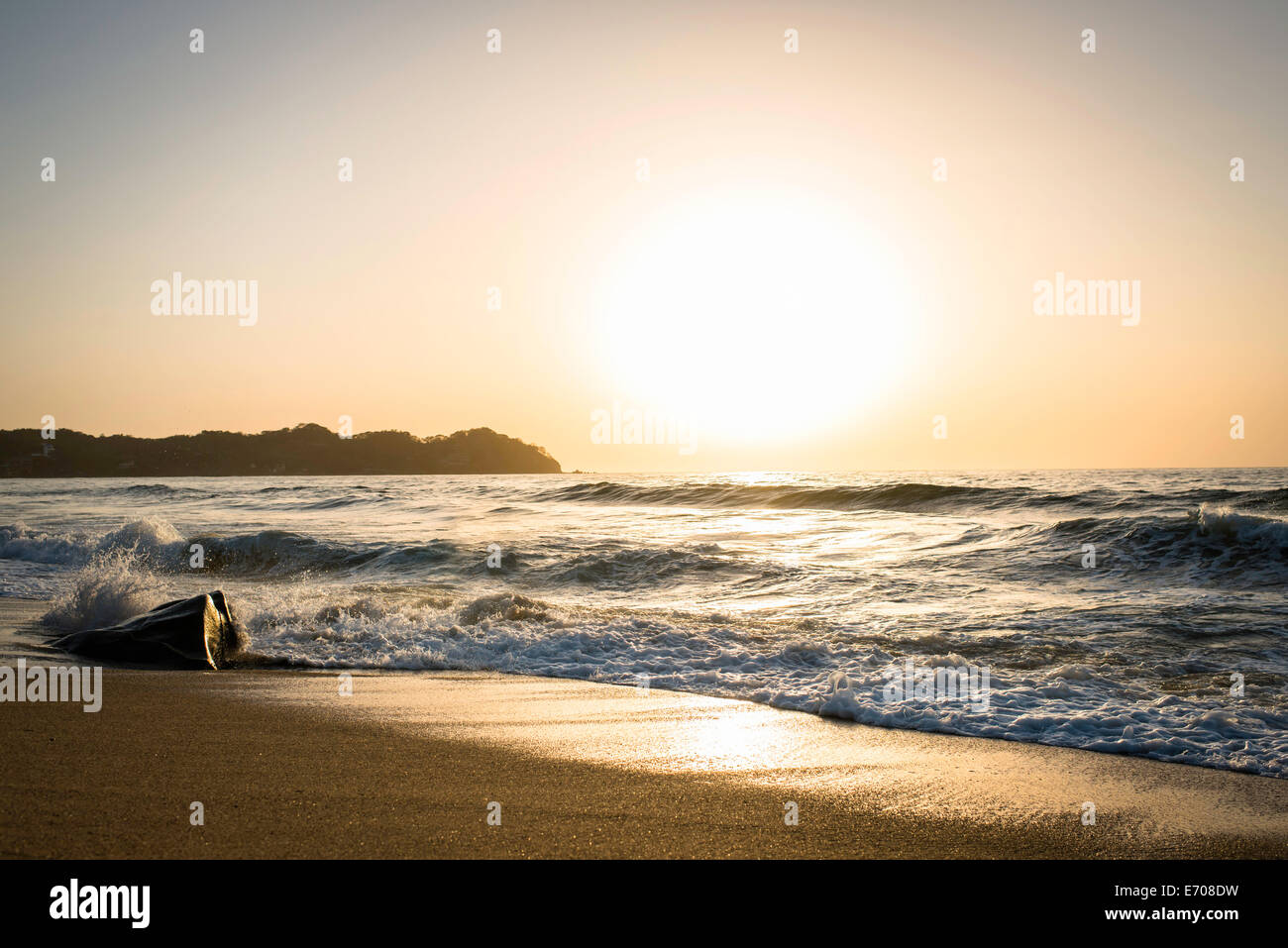Les vagues de l'océan et le sable au coucher du soleil Banque D'Images