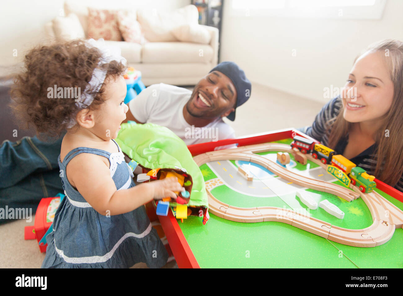 Mère et père jouant avec sa jeune fille, train set sur table Banque D'Images