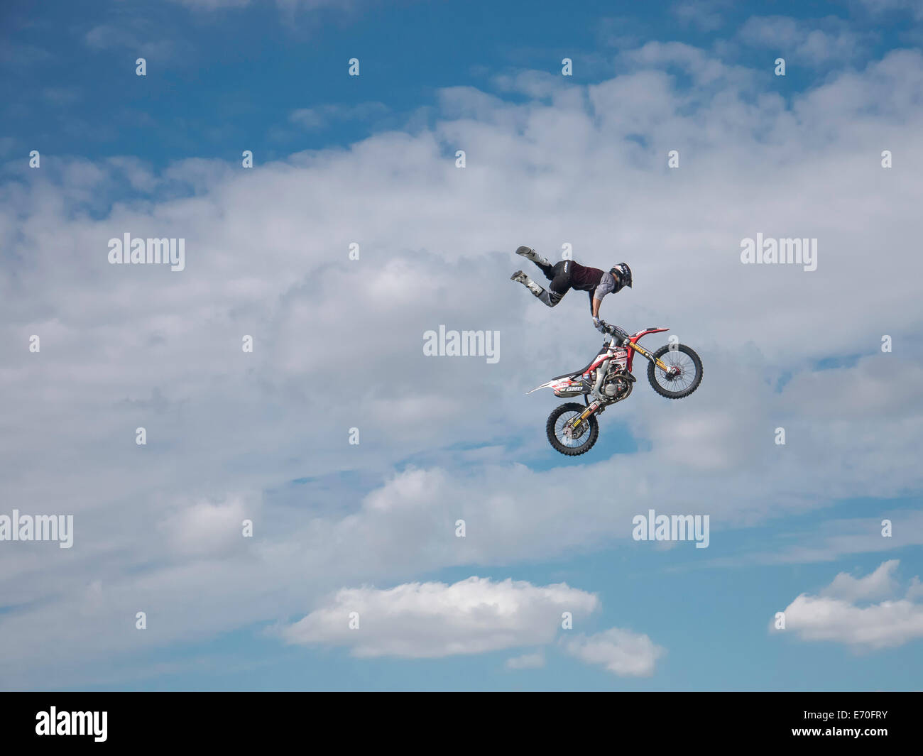 Moto FMX rider remplissant les cascades dans le contexte d'un ciel bleu avec des nuages Banque D'Images