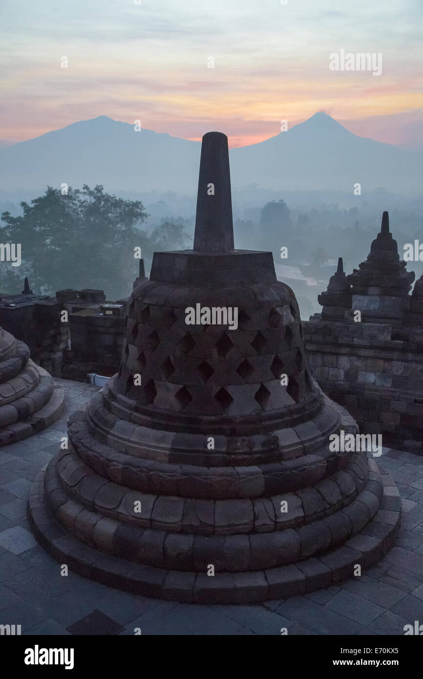Borobudur, à Java, en Indonésie. Stupa et le Mont Merapi au lever du soleil dans la brume du matin. Banque D'Images