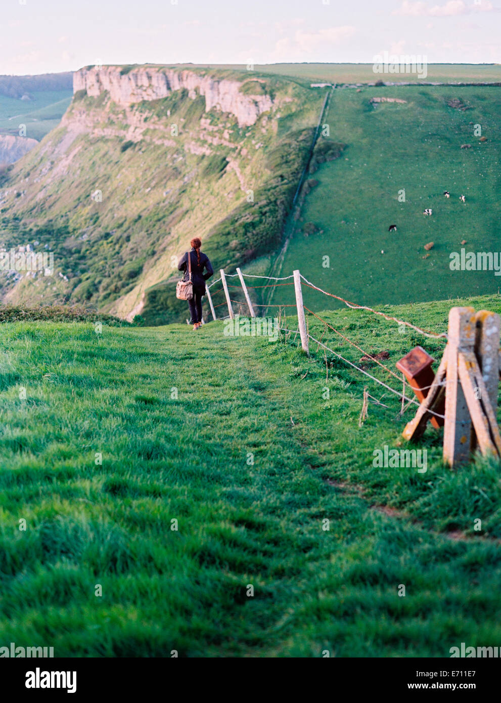 Une femme marche le long d'une clôture sur une falaise chemin. Vue sur le paysage. Banque D'Images