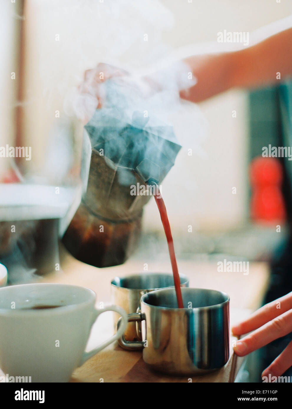 Une personne titulaire d'un percolateur à café et verser le café chaud dans les tasses. Banque D'Images
