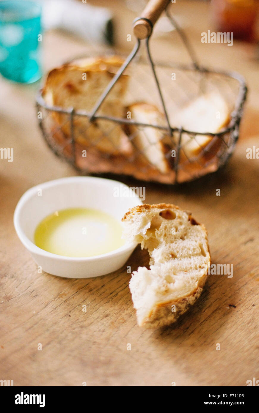 Tranches de pain dans un panier, une tranche à moitié mangé et un plat d'huile. Banque D'Images