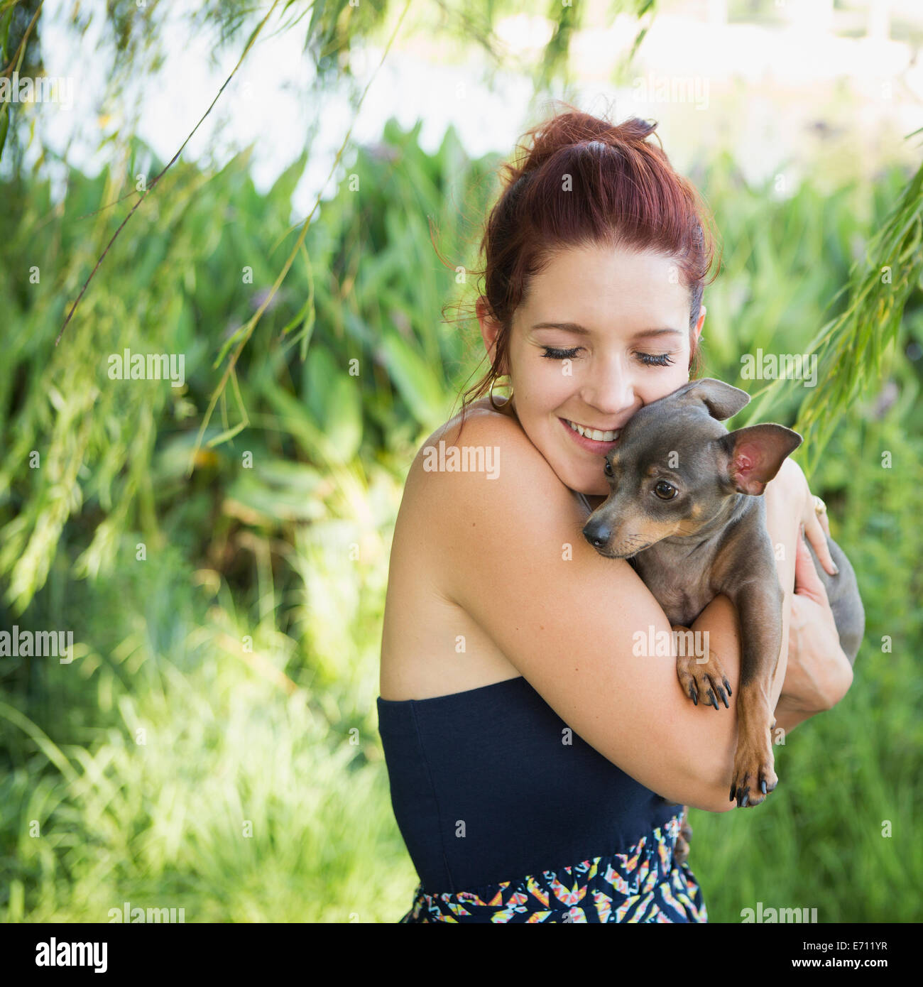 Une femme, berçant un petit chien de compagnie. Banque D'Images Une femme, berçant un petit chien de compagnie. Banque D'Images