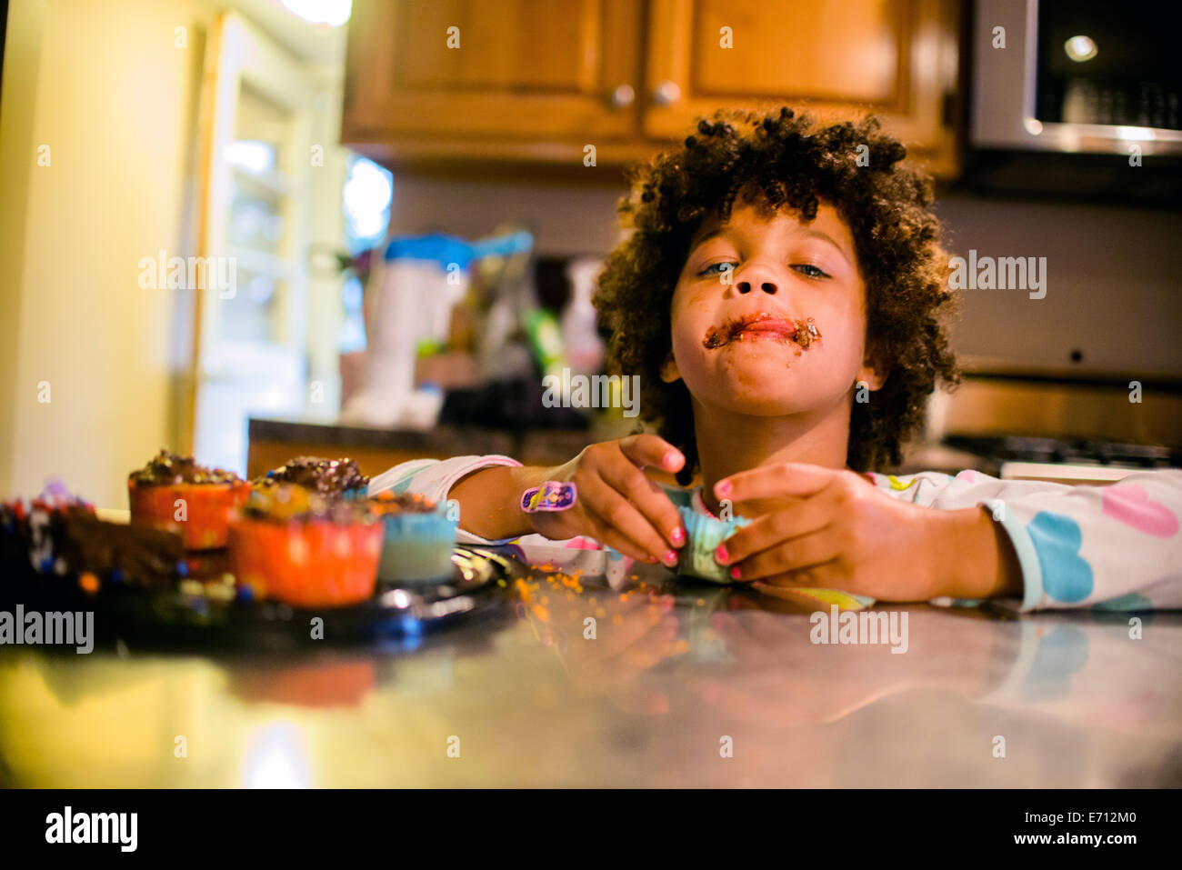 Portrait de fille avec la bouche de chocolat cupcakes manger Banque D'Images