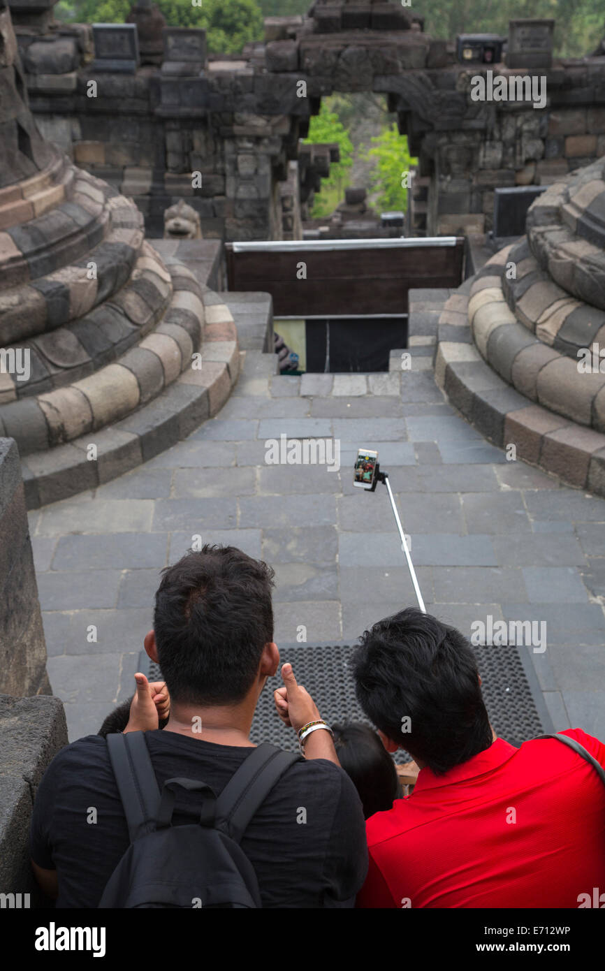 Borobudur, à Java, en Indonésie. Quatre jeunes Indonésiens en utilisant une extension de prendre un poteau tout en visitant le Temple Selfies. Banque D'Images