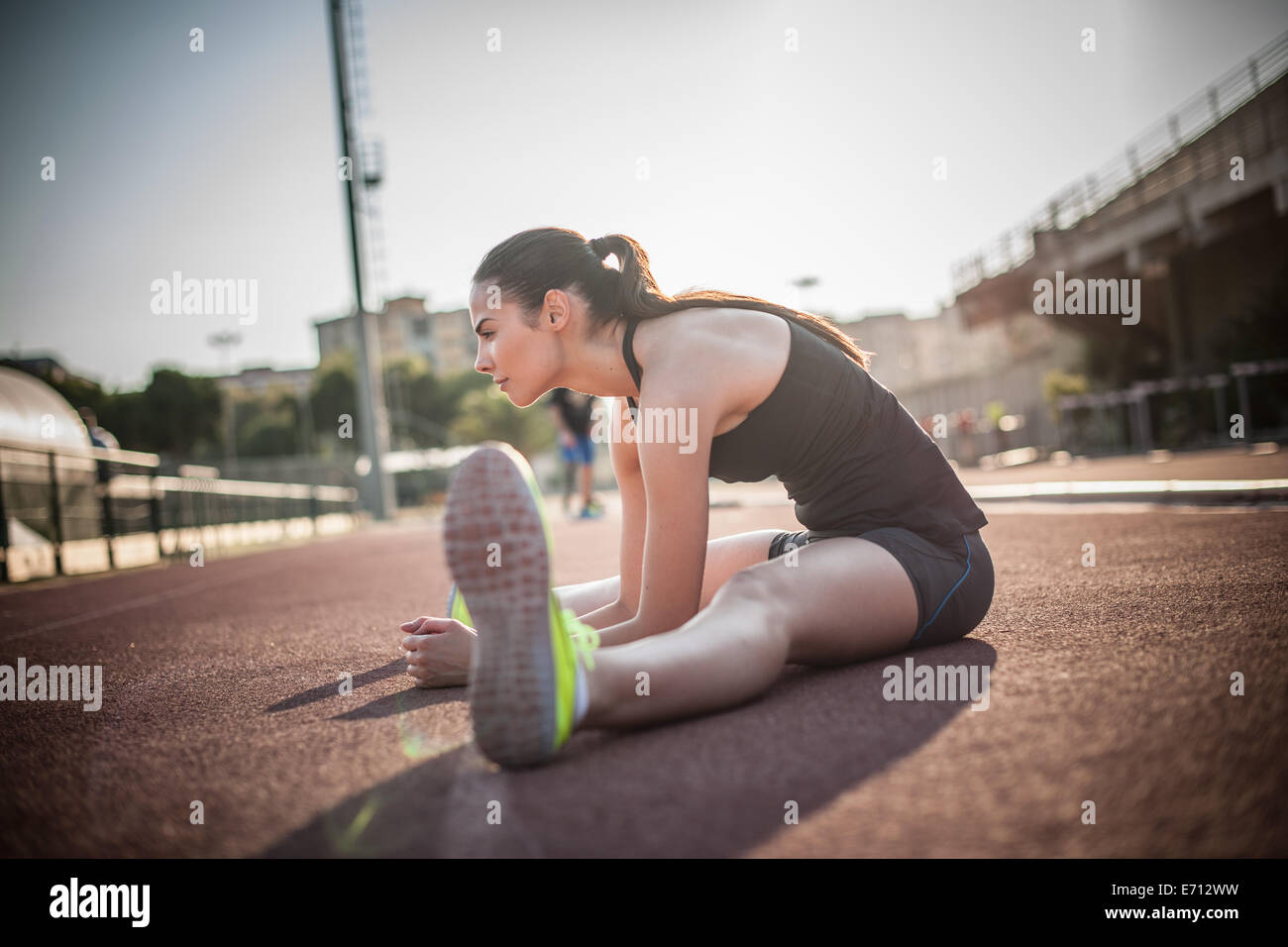 Femme assise sur le sol jambes étirement Banque D'Images