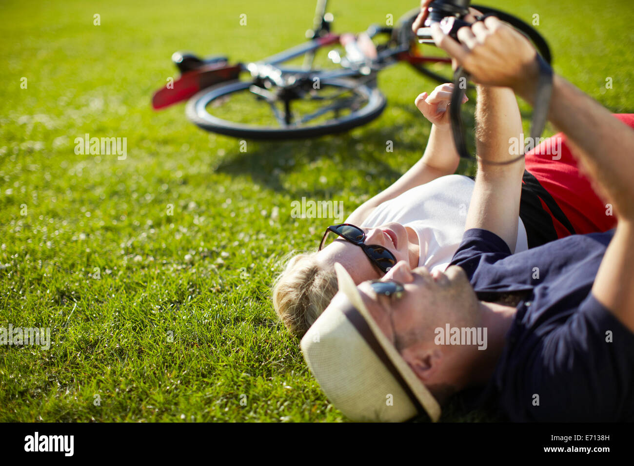 Couple lying in park looking at photographs sur appareil photo numérique Banque D'Images
