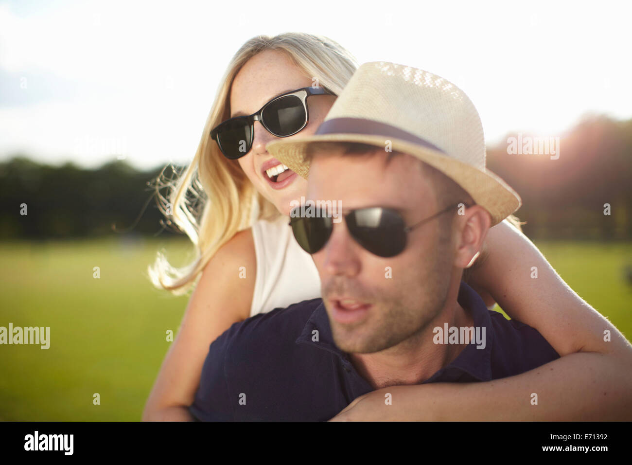 Jeune femme avec bras autour de petit ami en park Banque D'Images