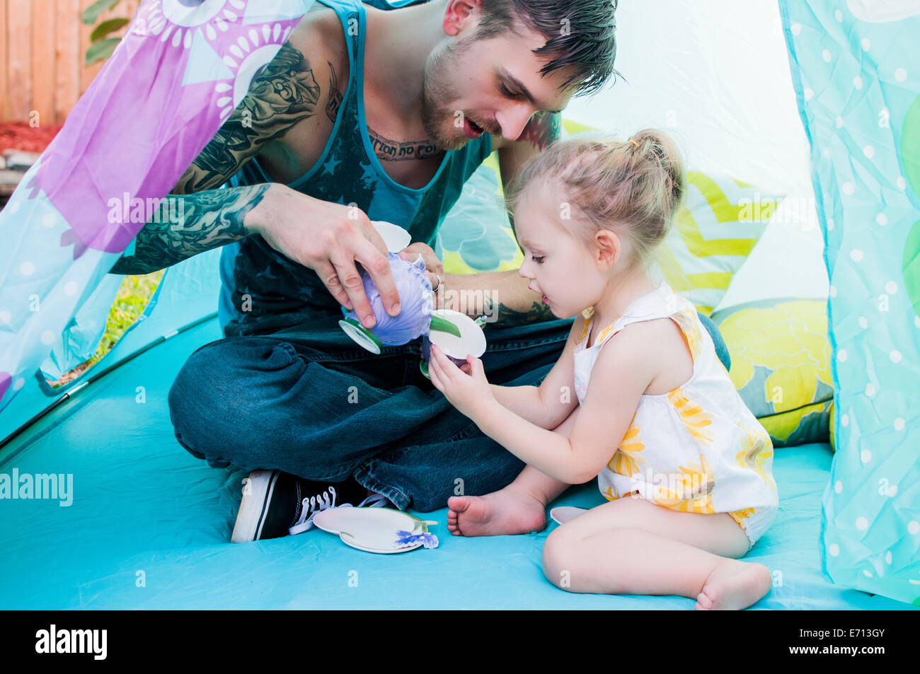 Jeune homme et enfant fille jouer avec verre en tente Banque D'Images
