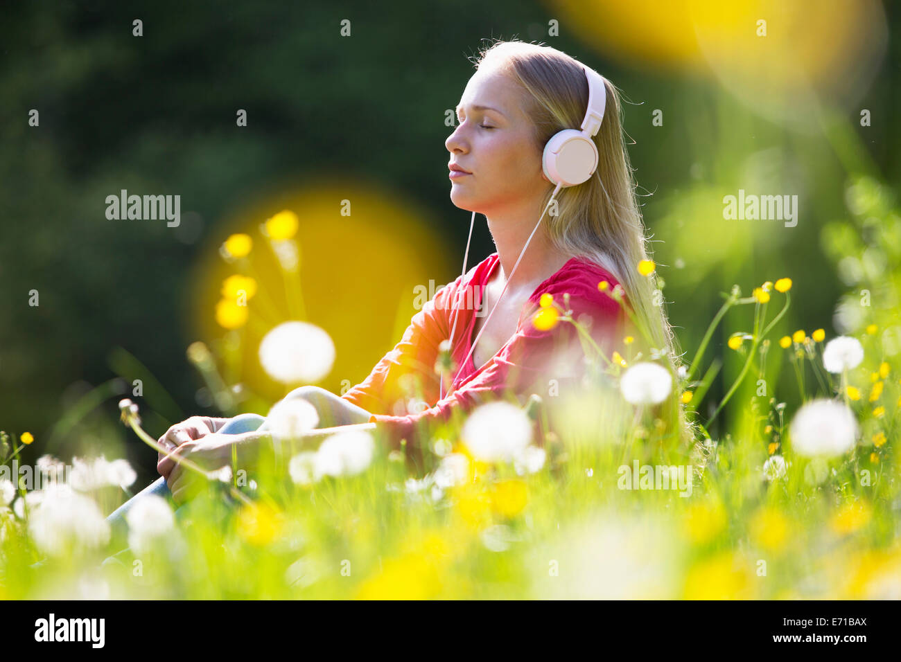 Portrait of teenage girl with headphones entendre de la musique sur une prairie de fleurs Banque D'Images