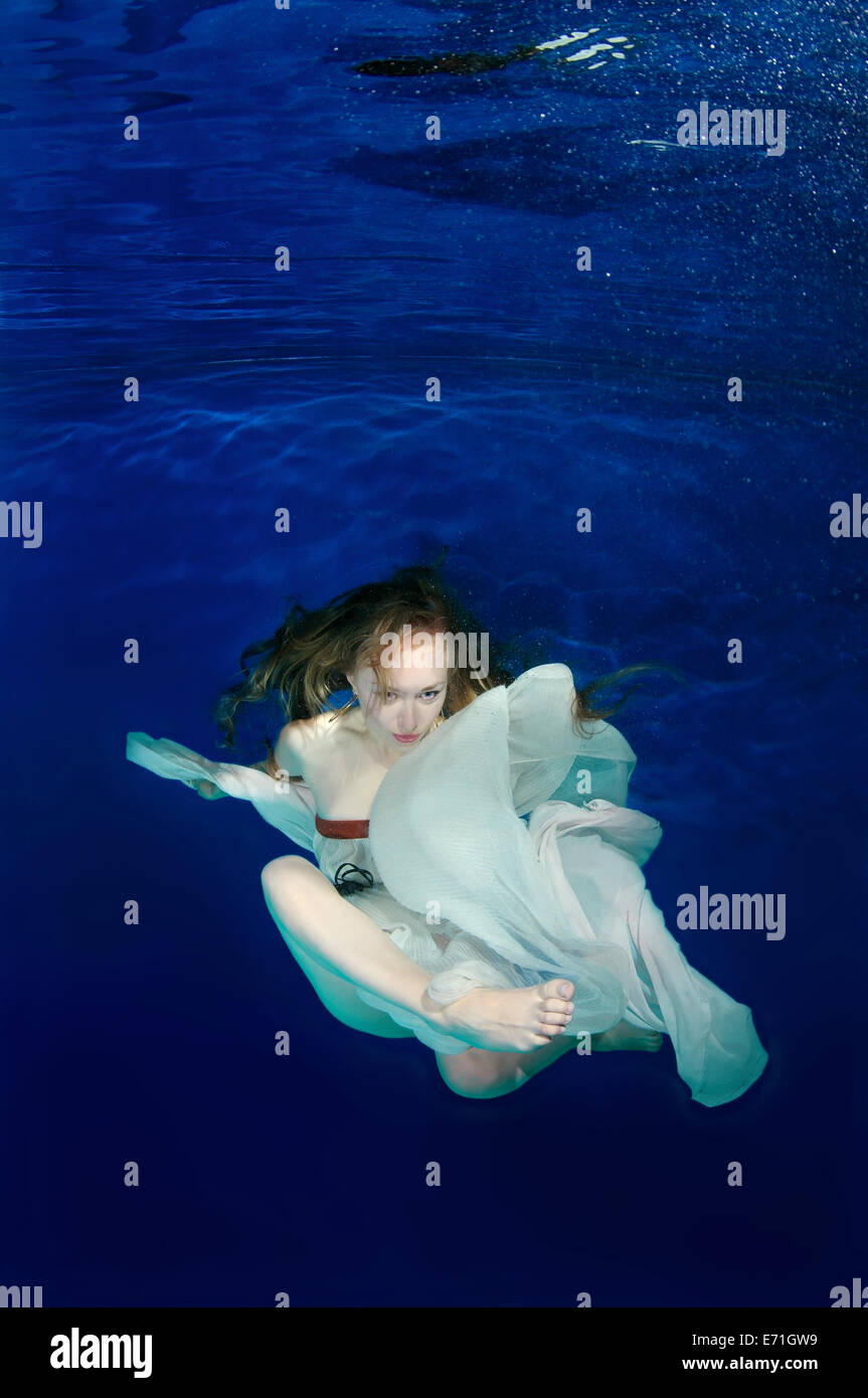 Une jeune femme avec de grands cheveux de poser dans un pool underwater Banque D'Images