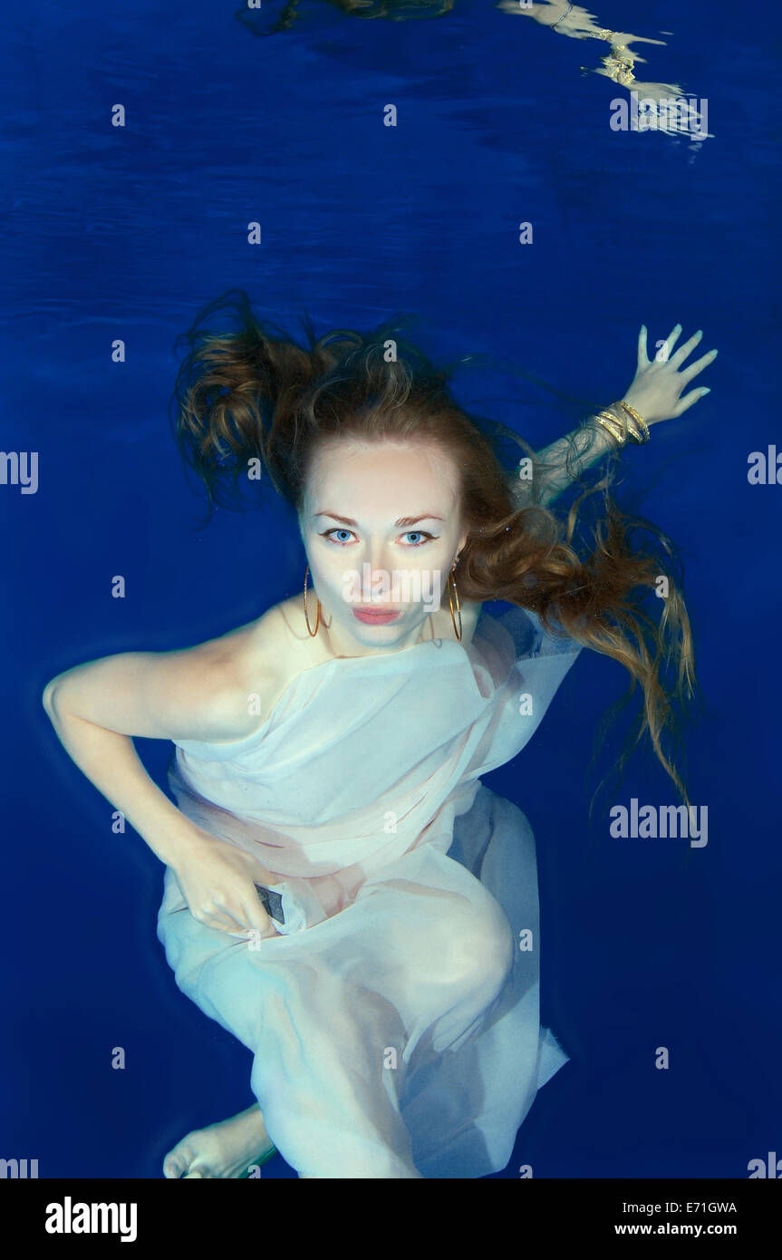 Une jeune femme avec de grands cheveux de poser dans un pool underwater Banque D'Images