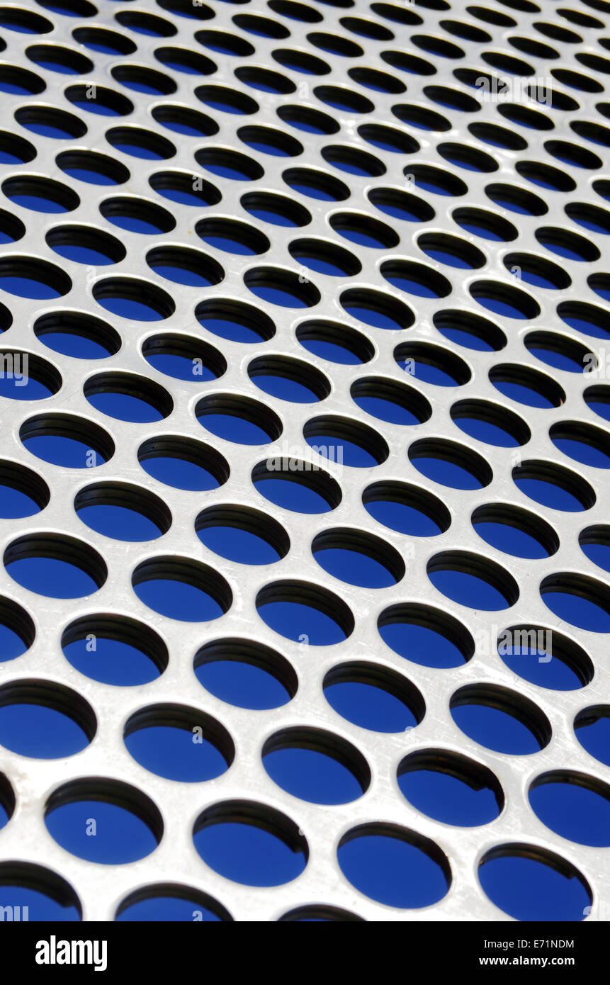 Grille perforée en aluminium contre un ciel bleu sous la lumière du soleil Banque D'Images