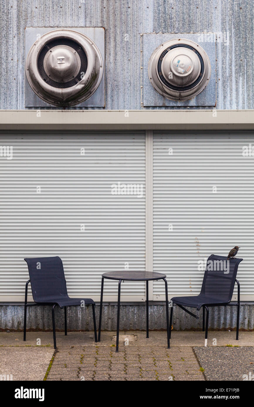 Image abstraite de chaises vides et une table avec un oiseau solitaire, Granville Island, Vancouver Banque D'Images