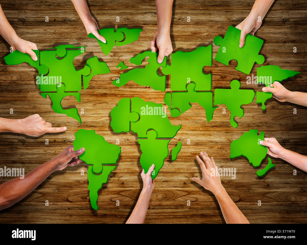 Groupe de mains tenant Puzzle Monde Jigasw formant Banque D'Images