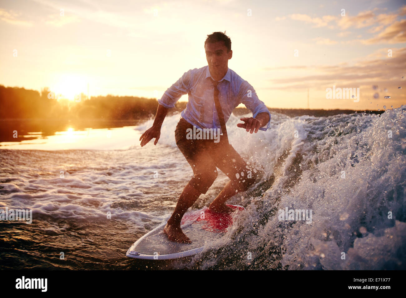 Jeune homme dans des vêtements mouillés surf at summer resort Banque D'Images