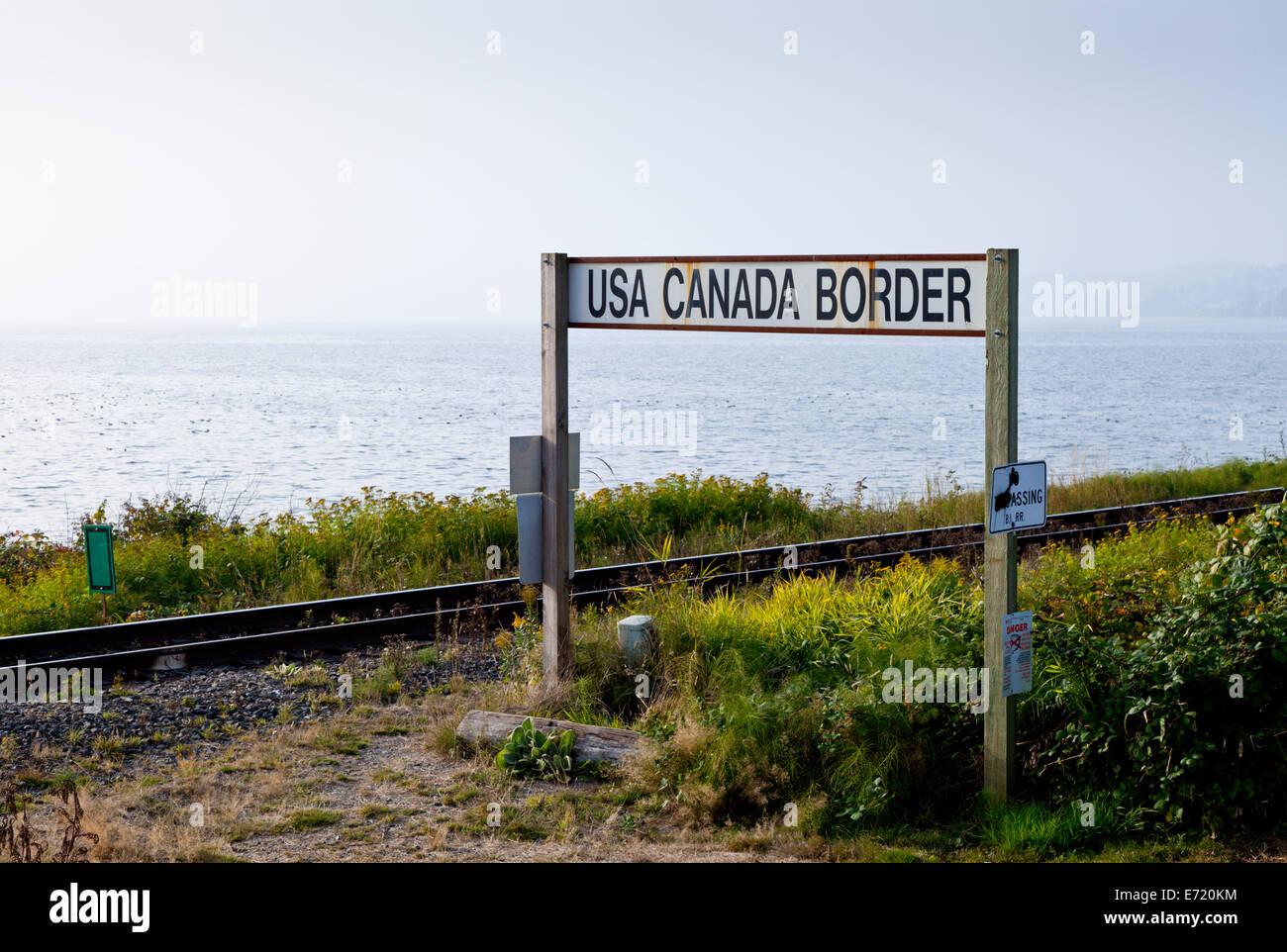 Marqueur de l'USA frontière canadienne avec une voie de chemin de fer et la mer derrière. Banque D'Images