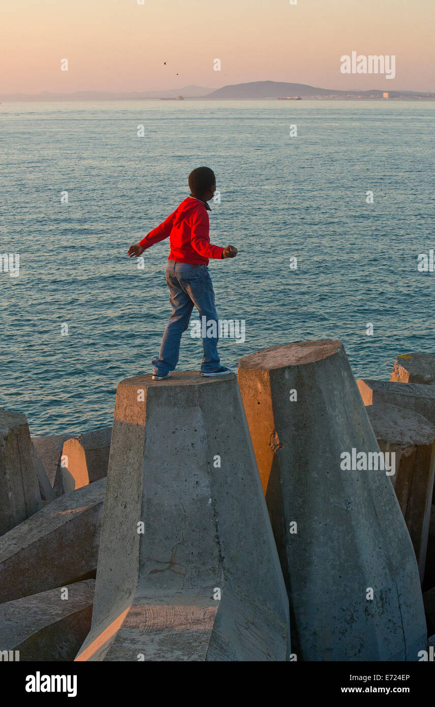 Garçon en train de lancer un caillou au Victoria & Alfred Waterfront Jetée Banque D'Images