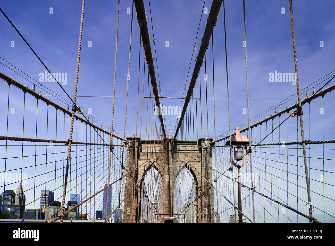 USA, New York, Manhattan, pont de Brooklyn. Vue sur pont vers Manhattan skyline partie encadrée par le centre de la tour de pierre et traversée par des fils d'acier et les câbles de suspension. Banque D'Images