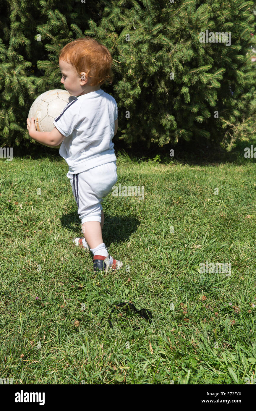 Adorable petit enfant garçon avec ballon de soccer dans le parc de la nature à l'été. L'utiliser pour bébé, éducation ou le concept d'amour Banque D'Images