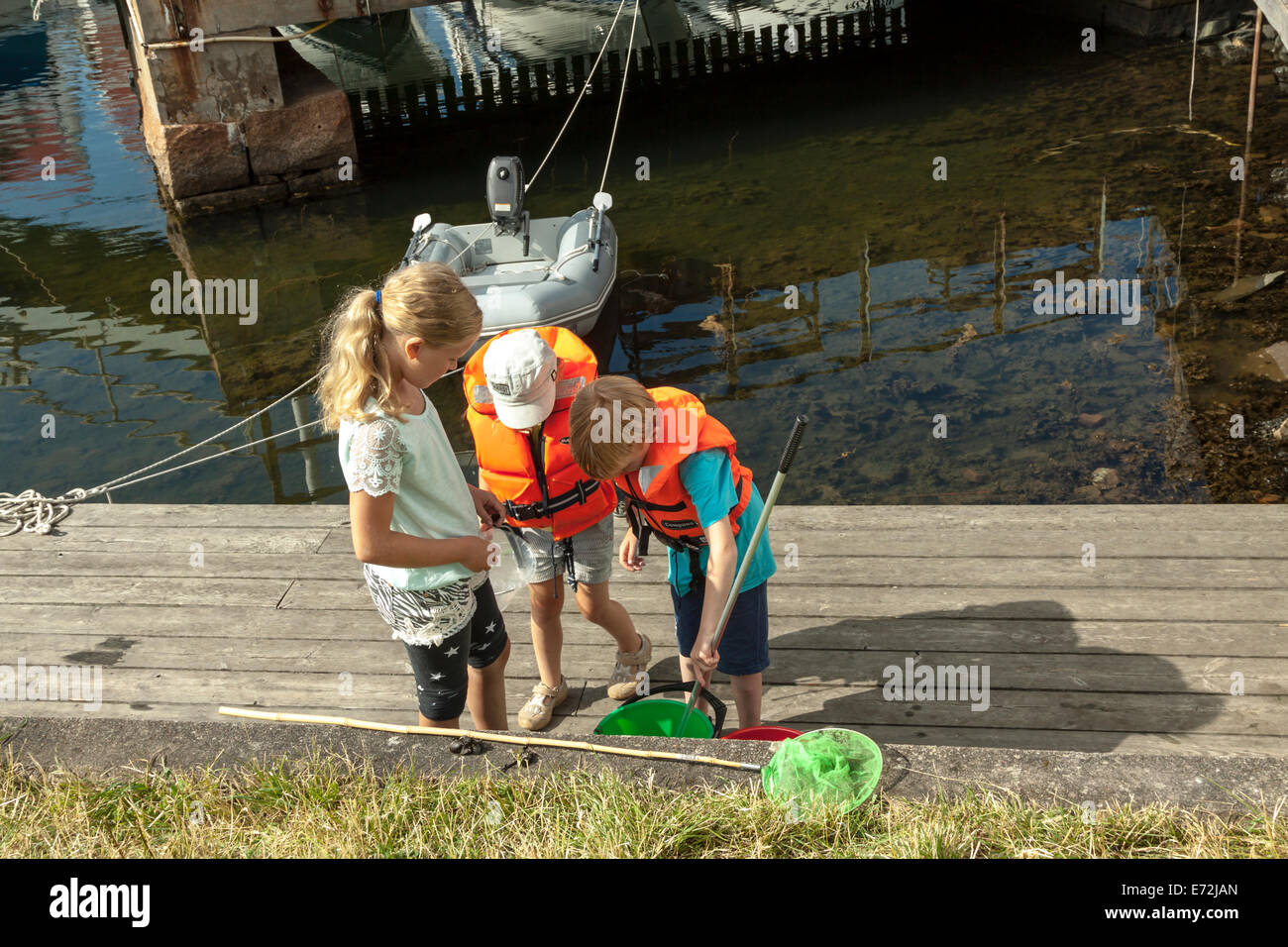 Les enfants à regarder leur prise du jour, dans le port d'Åstol, une île dans l'archipel suédois, Suède. Banque D'Images