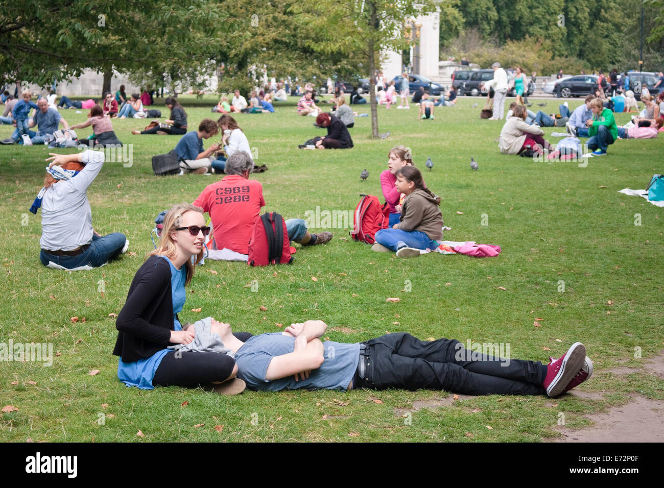 Les gens se détendre sur l'herbe à l'extérieur de Buckingham Palace, London, UK Banque D'Images