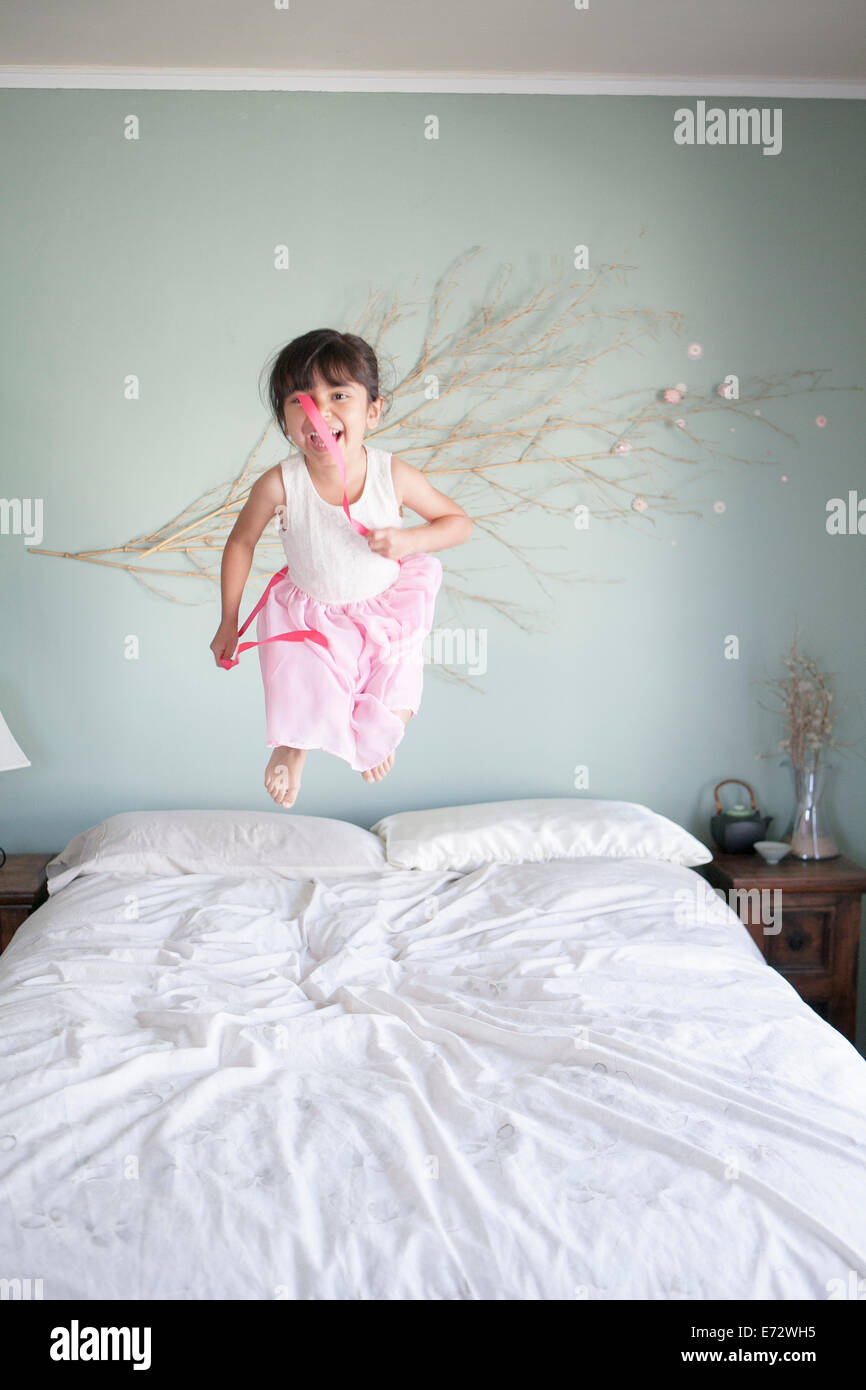Girl (6-7) jumping on bed with lollipops dans la main Banque D'Images