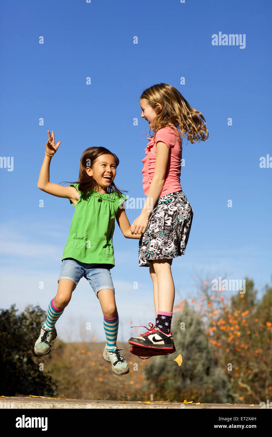 Les filles (10-12) holding hands and jumping Banque D'Images