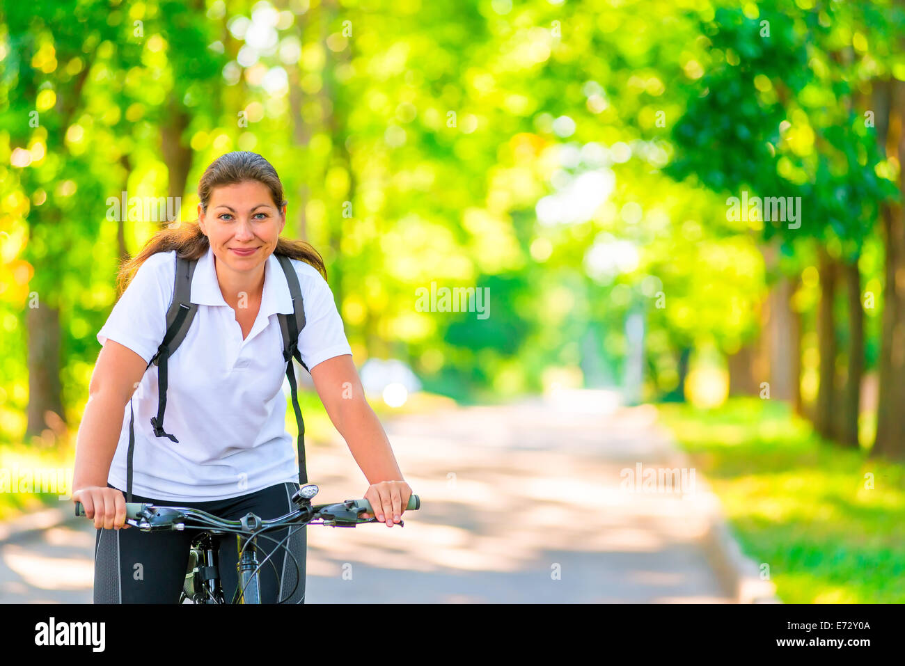 Cheerful belle cyclist riding a bike Banque D'Images