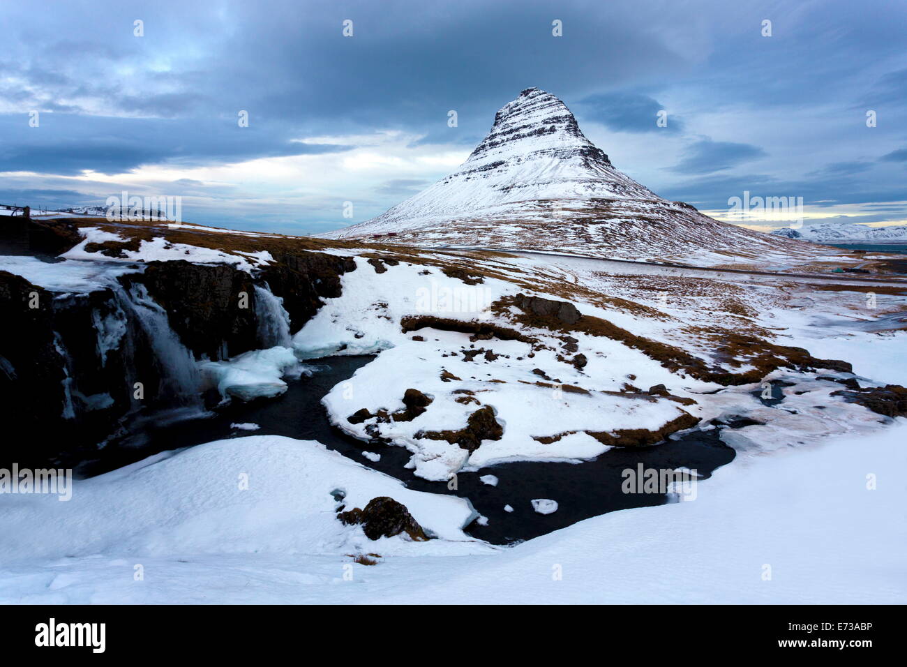 Kirkjufell recouvert de neige avec une rivière gelée et cascade au premier plan, Grundarfjordur, Péninsule de Snæfellsnes, l'Islande Banque D'Images