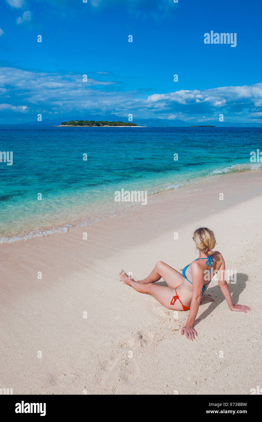 Une femme assise sur la plage de sable blanc de Beachcomber Island, îles Mamanucas, Fidji, Pacifique Sud, du Pacifique Banque D'Images Une femme assise sur la plage de sable blanc de Beachcomber Island, îles Mamanucas, Fidji, Pacifique Sud, du Pacifique Banque D'Images