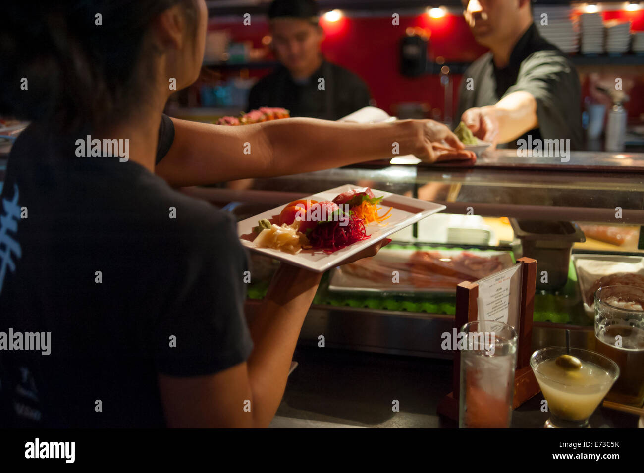Serveur serveuse ramasser des plats de sushis préparés à prendre pour les clients Banque D'Images