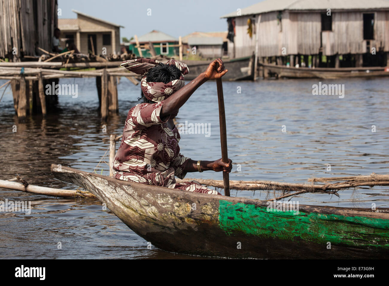 L'Afrique, Bénin, Ganvie. Femme en costume traditionnel l'aviron en pirogue sur le Lac Nokoué village guindée. Banque D'Images