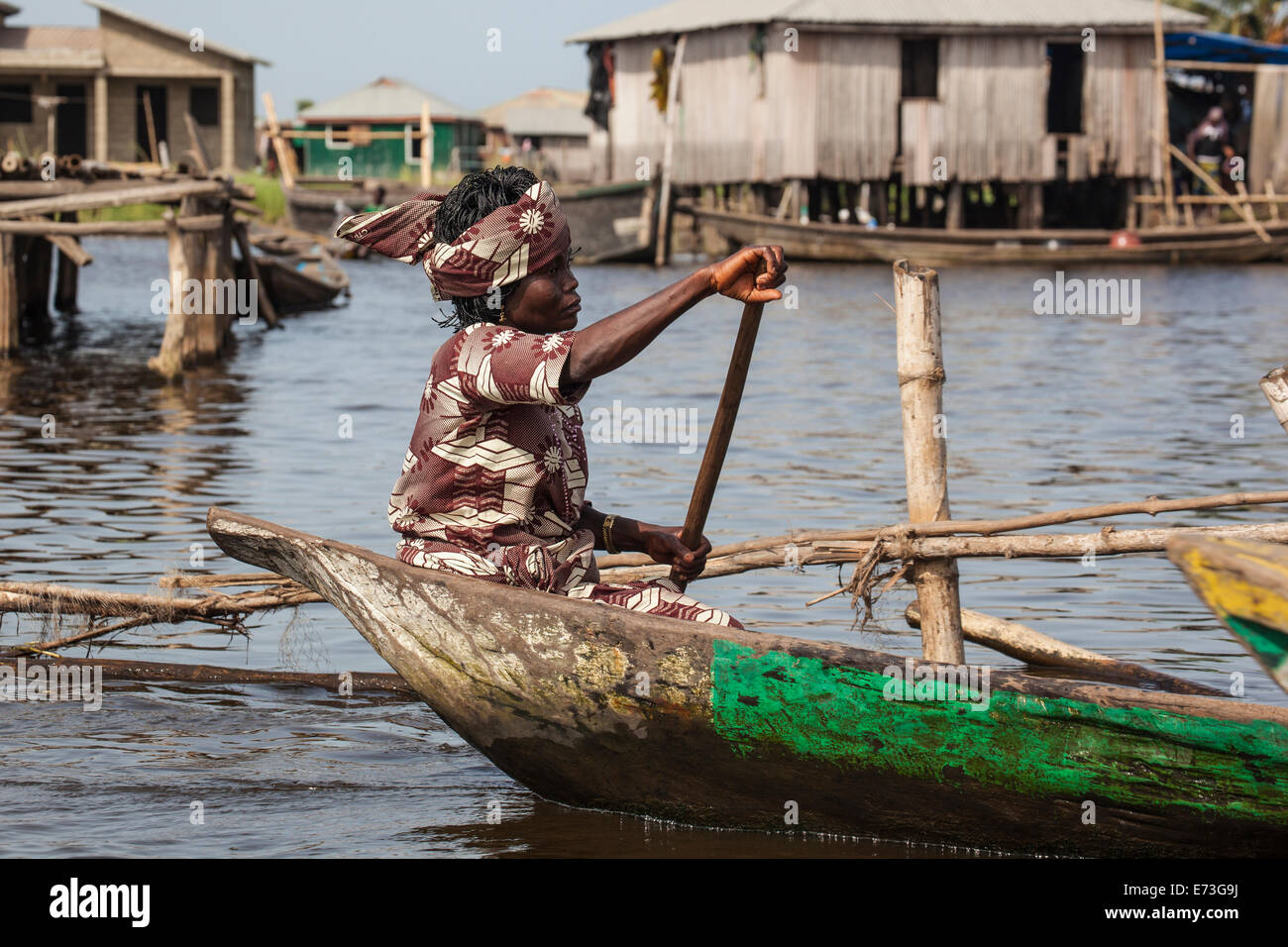 L'Afrique, Bénin, Ganvie. Femme en costume traditionnel en pirogue aviron Lac Nokoué village guindée. Banque D'Images