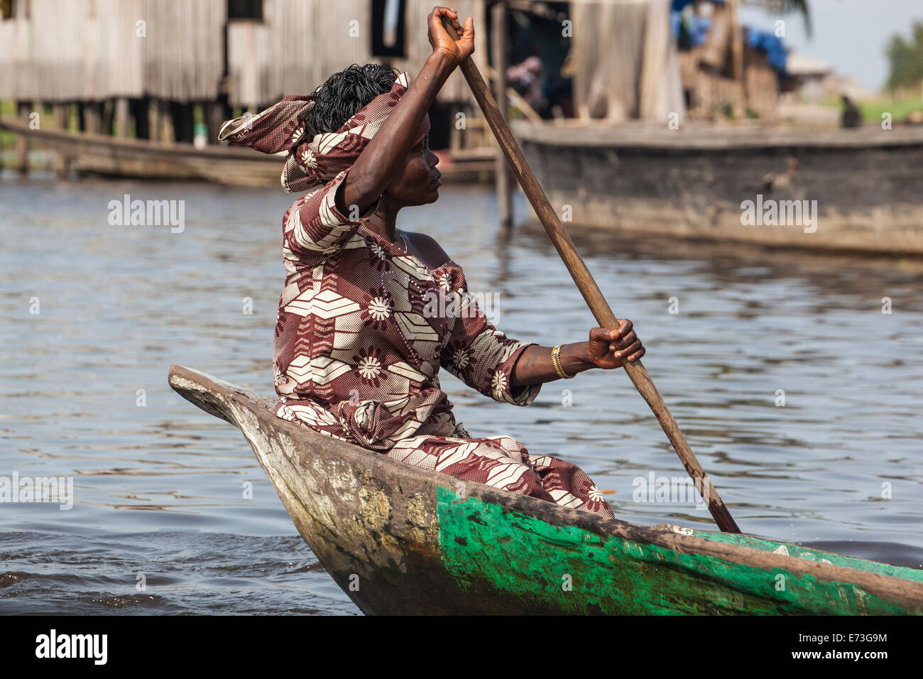 L'Afrique, Bénin, Ganvie. Femme en costume traditionnel l'aviron en pirogue sur le Lac Nokoué village guindée. Banque D'Images