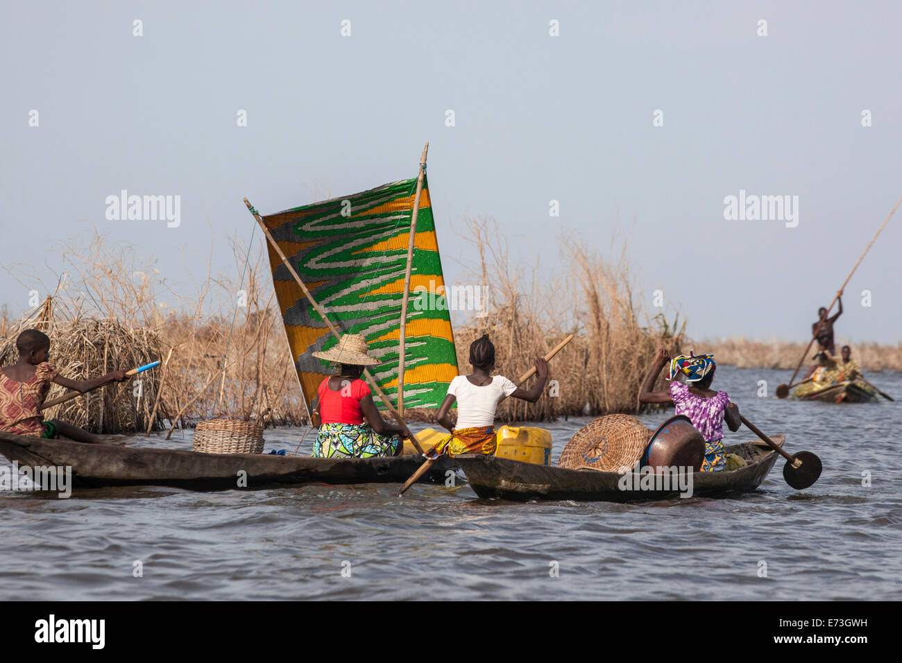 L'Afrique, Bénin, Ganvie. Les femmes paddling pirogue avec voile coloré sur le Lac Nokoué. Banque D'Images