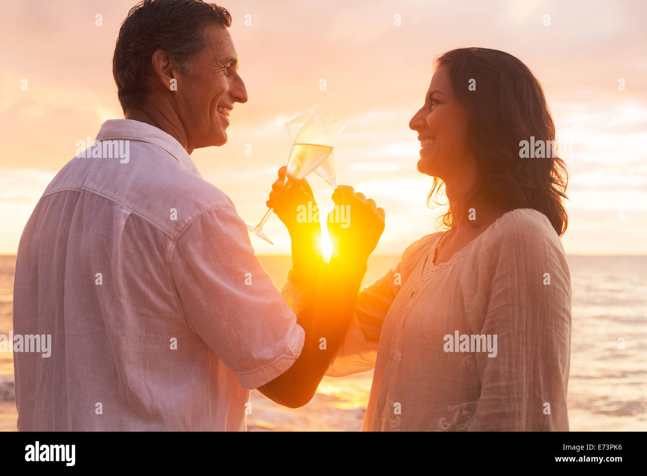 Happy Romantic Couple Enjoying verre de champagne au coucher du soleil sur la plage. La retraite de voyages vacances anniversaire. Banque D'Images
