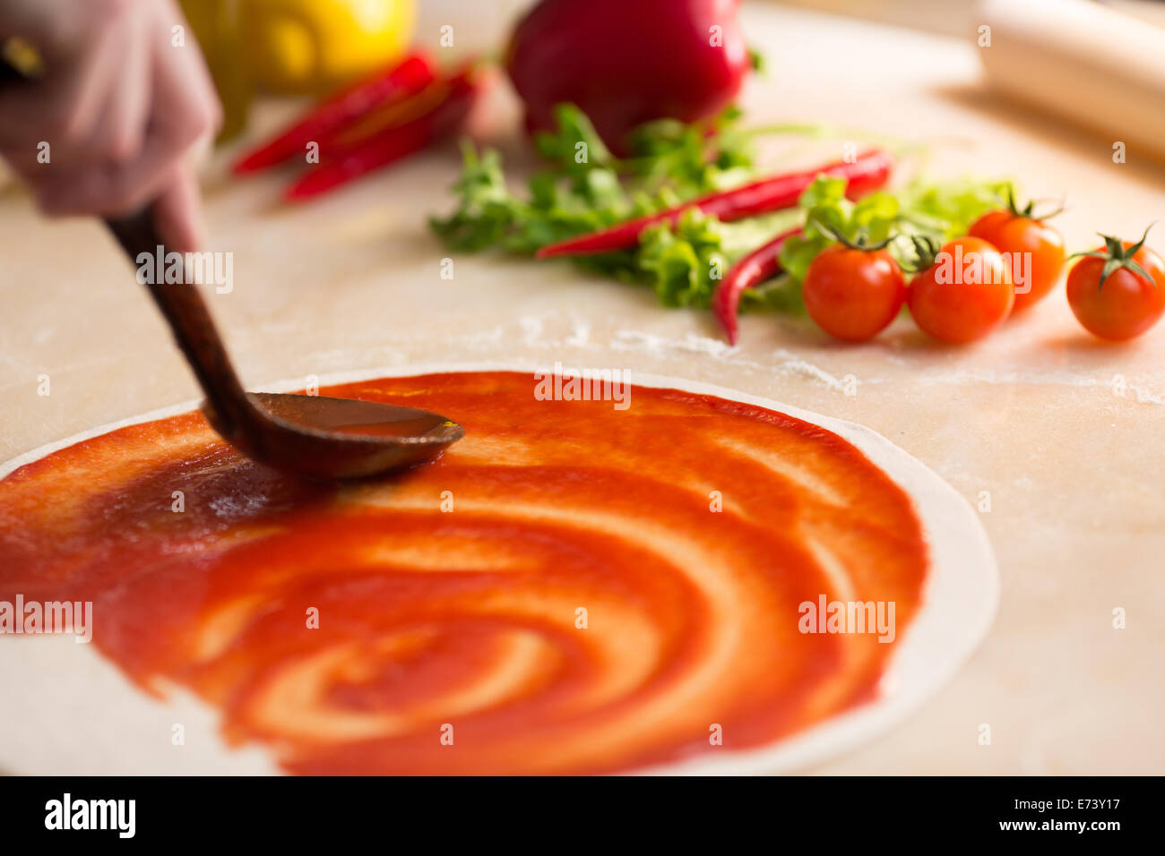L'ajout de sauce. Préparation de la pizza italienne. Banque D'Images