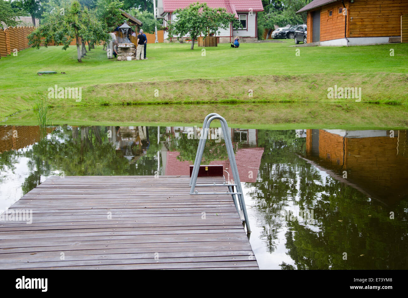 Étang rural avec grande planche pont sur fond de cour village Banque D'Images