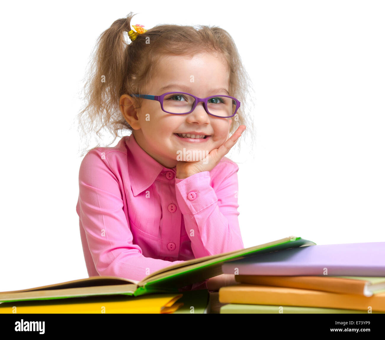 Happy smiling kid girl dans les verres la lecture de livres sitting at table Banque D'Images