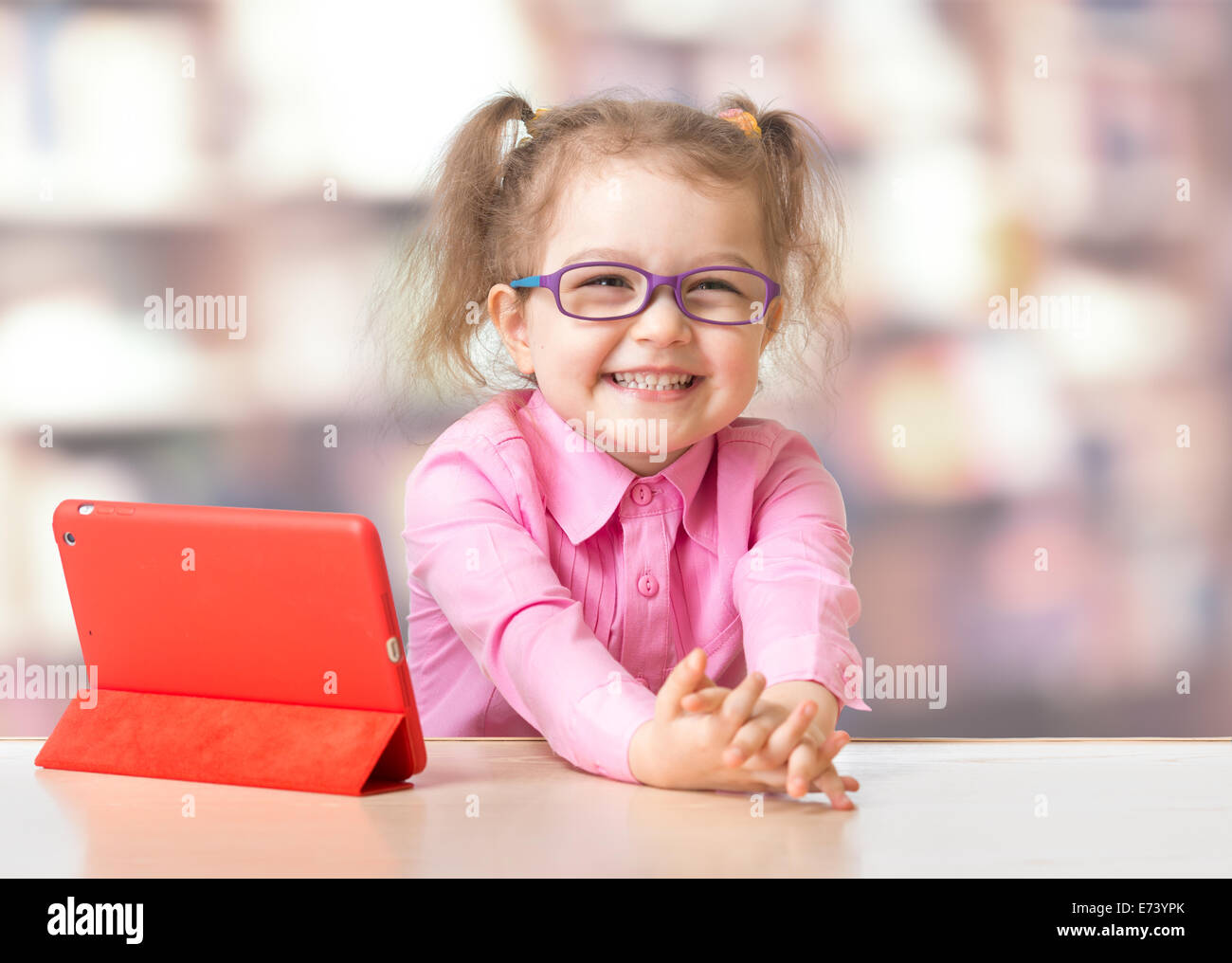 Enfant assis à l'ordinateur tablette dans la chambre Banque D'Images