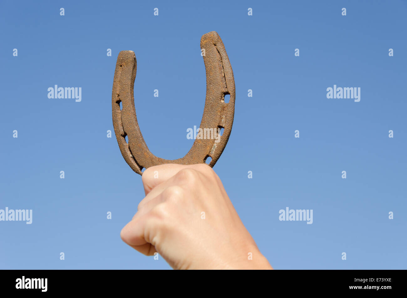 La main féminine vieux fer rouillé à cheval sur fond de ciel bleu, symbole de chance de bonheur Banque D'Images