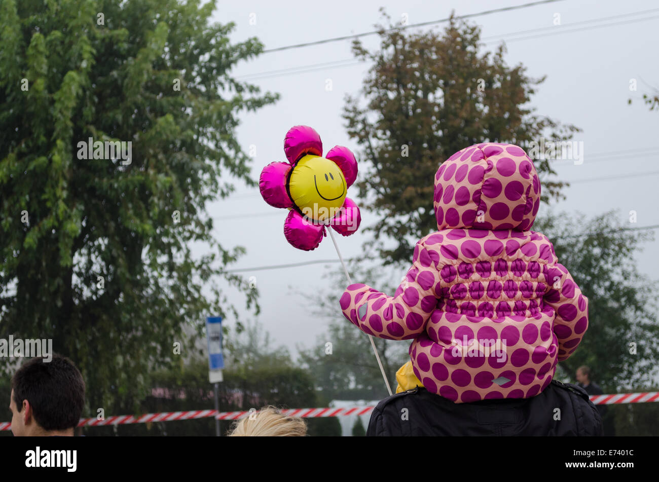 Petite fille aux fleurs rose veste en pointillés et ballon forme siéger le père épaules Banque D'Images