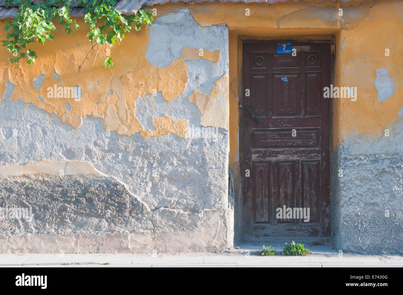 Un mur avec des travaux de plâtre jaune écaillée et une porte en bois de Konya, Turquie Banque D'Images
