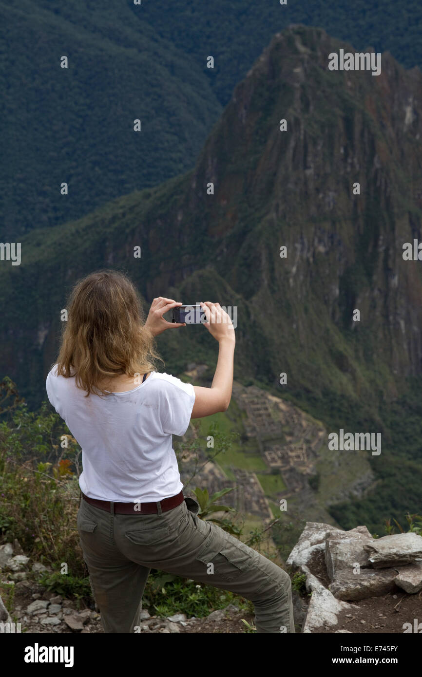 Un touriste prend photo du Machu Picchu sanctuaire avec son iPhone depuis le pic de la montagne du Machu Picchu au Pérou. Banque D'Images